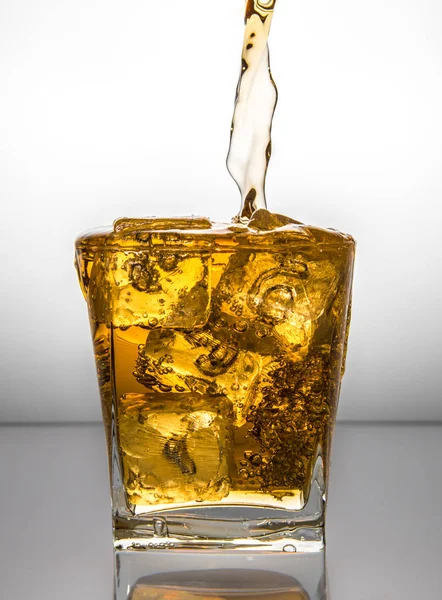 Glass with ice and liquid splash — Stock Photo, Image