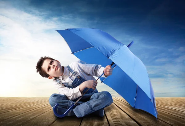 Pojke med öppen paraply tittar upp — Stockfoto