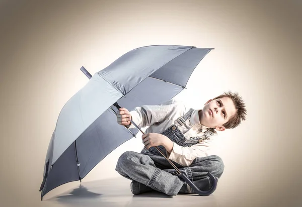 Pojke med öppen paraply tittar upp — Stockfoto