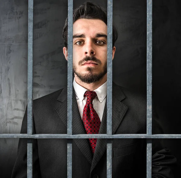 Молодой бизнесмен в тюрьме на темном фоне — стоковое фото