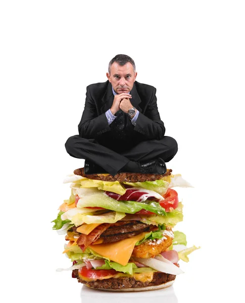 Obchodní muž sedí na velký sendvič v bílém pozadí — Stock fotografie
