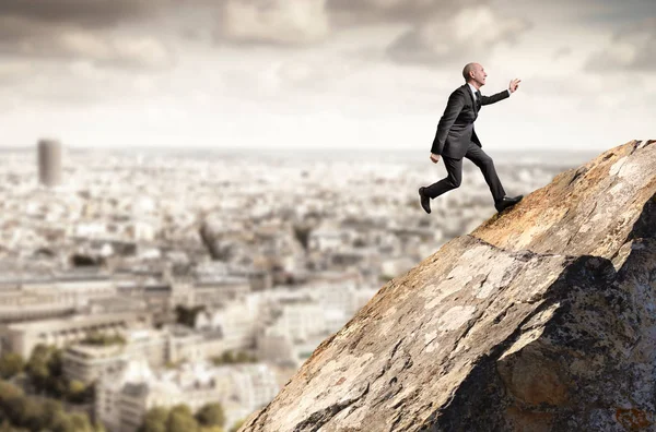 Hombre de negocios corriendo cuesta arriba desde una roca —  Fotos de Stock