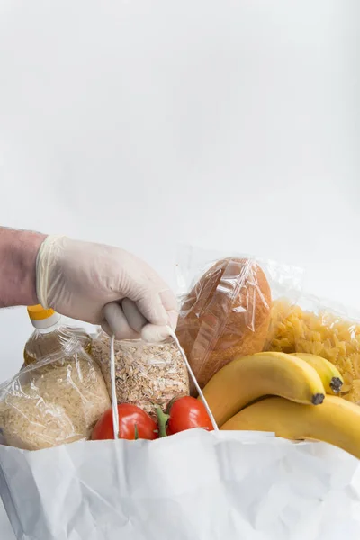 Man in rubber gloves holds the paper bag  with food. Donation food delivery