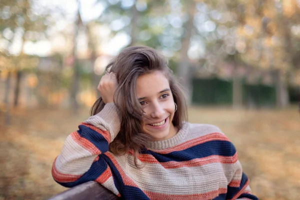 Дівчина сидить на лавці і захоплюється осінньою. Красива дівчина посміхається, сидячи на лавці восени . — стокове фото