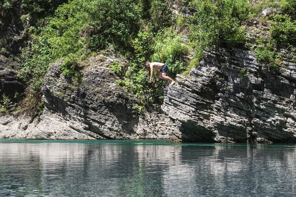 Een man springt van een klif in een rivier. Zomertijd, plezier, de mens springt als vissen van het meer, zwemt, geniet van tijd doorbrengen op zomervakantie. — Stockfoto