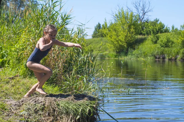 Kleines Mädchen, das mit einem Spritzer durch das Wasser rennt. in ihren Händen Tuch. — Stockfoto