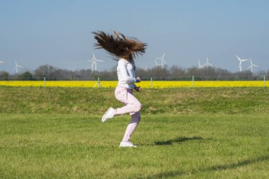 Çimlerin üzerinde zıplayan genç bir kız, sporun doğasında olan bir kız. Doğadaki kız akrobatik dublörler yapar.