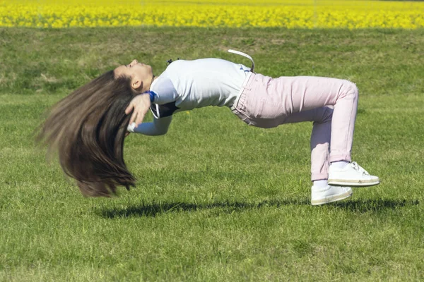 草の上を飛び跳ねる若い女の子、スポーツの性質の女の子。自然の上の女の子はアクロバットスタントを行います. — ストック写真