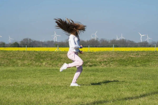Een jong meisje springen op het gras, een meisje in de aard van de sport. Meisje op de natuur doet acrobatische stunts. — Stockfoto