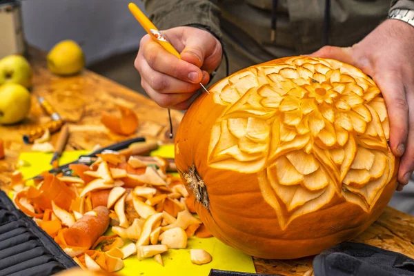 Processen att skära Halloween pumpor,. Mäns händer med knivskuren pumpa.Mäns händer snidar mönster på en pumpkin.Halloween förberedelse. — Stockfoto