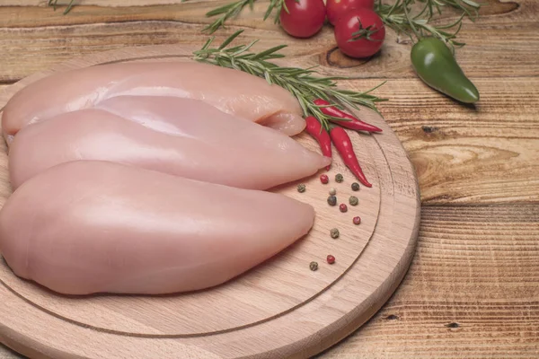 Surowe piersi kurczaka i przyprawy na drewnianej desce do krojenia, widok z bliska. Świeży surowy filet z kurczaka na drewnianej desce do krojenia. — Zdjęcie stockowe