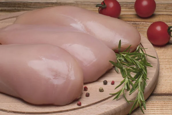 Surowe piersi kurczaka i przyprawy na drewnianej desce do krojenia, widok z bliska. Świeży surowy filet z kurczaka na drewnianej desce do krojenia. — Zdjęcie stockowe