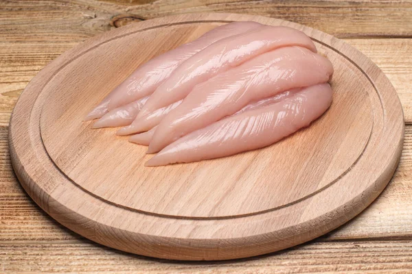 Surowy, świeży, mały filet z kurczaka. Mały wewnętrzny filet z kurczaka na drewnianej desce do krojenia. — Zdjęcie stockowe