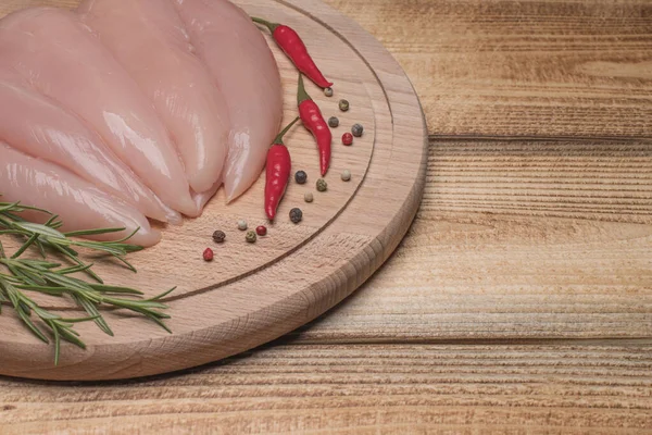 Raw, fresh small inner chicken fillet. Small inner chicken fillet on a wooden cutting board.