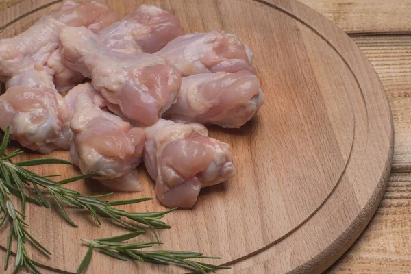 Fresh raw chicken wings on a wooden cutting board.