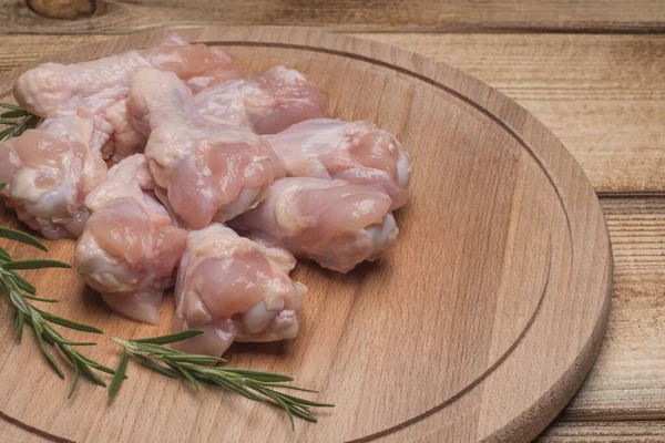 Fresh raw chicken wings on a wooden cutting board.