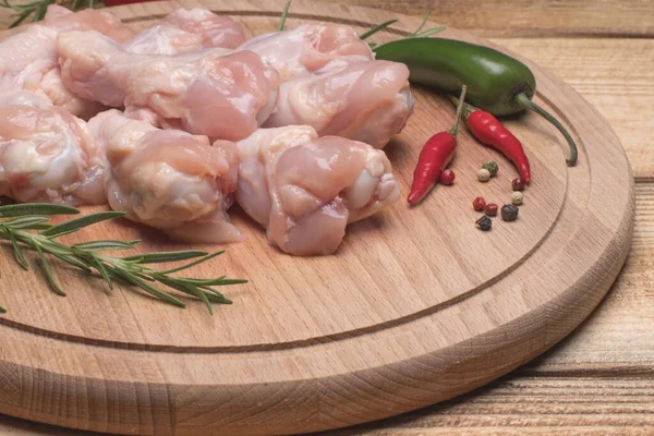 Fresh raw chicken wings on a wooden cutting board.