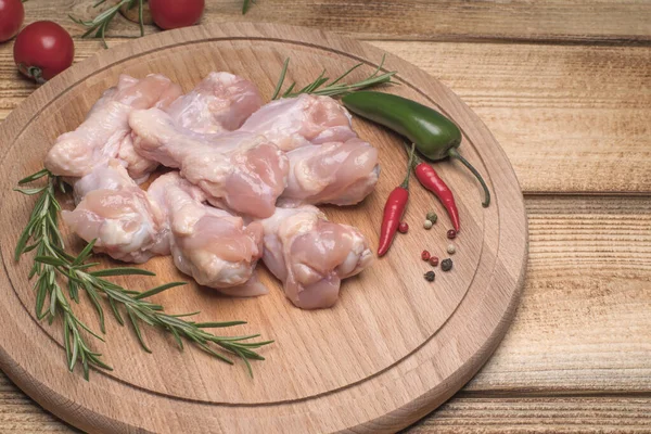 Fresh raw chicken wings on a wooden cutting board.