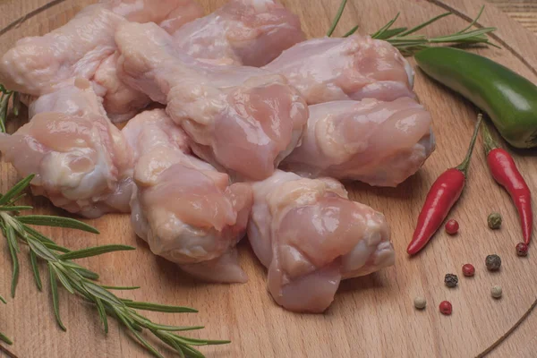 Fresh raw chicken wings on a wooden cutting board.