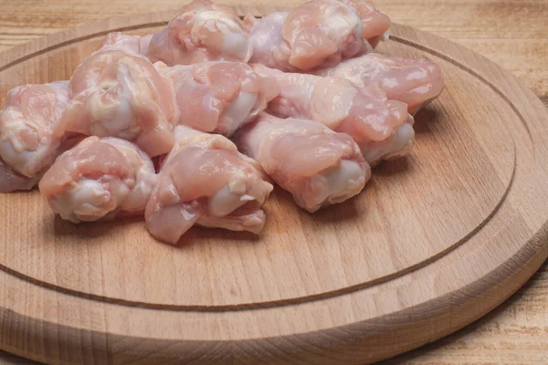 Fresh raw chicken wings on a wooden cutting board.