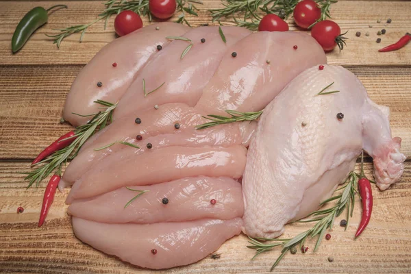 Raw, fresh chicken meat platter on a wooden surface with spices for cooking.Raw chicken meat on wooden board. Healthy eating