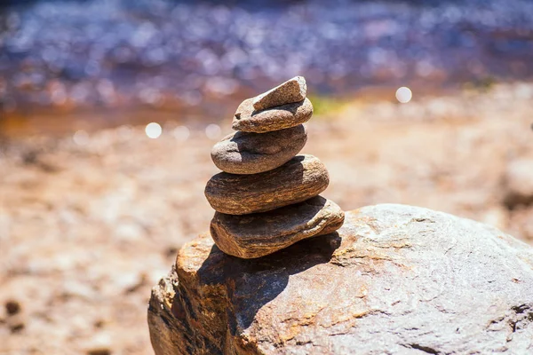 Natuurstenen piramides op de oever van de rivier. Stenen balans close-up.Close-up abstract beeld van stenen gebalanceerd als piramide. — Stockfoto