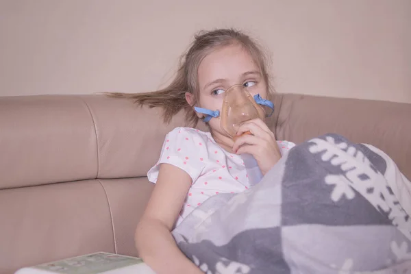 La niña pequeña inhala en casa. La niña está enferma, se trata con inhalación. . —  Fotos de Stock
