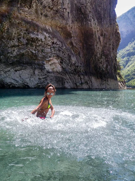 Meisje speelt in het water met spetters. Een meisje rust uit op de rivier met een prachtig uitzicht op de bergen van Albanië. — Stockfoto