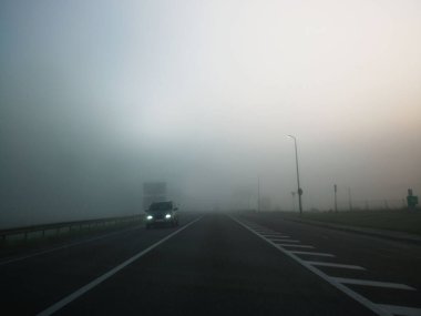 Araba siste yolda ilerliyor. Sisli ve soğuk bir günde otoyolda arabalar hızlı gidiyor. Yol güvenliği sorunu kavramı.