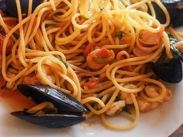 Cooked pasta with seafood mussels oysters krivetkami on a white plate close-up.