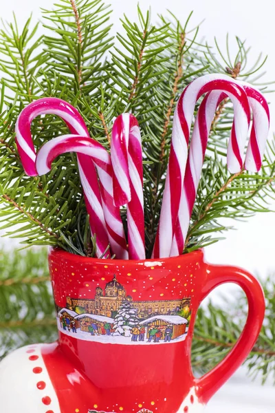 Red and white candy canes in red cup.Christmas candy canes in a red cup in the background Christmas tree. New Year concept.