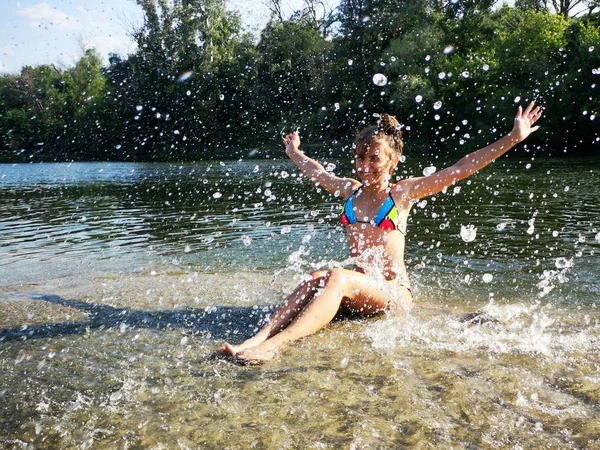 河里的女孩在泼水。穿着湿白色泳衣的性感的黑发女人在河里摆姿势。 年轻的雌性在玩水 夏天迷人的女孩. — 图库照片