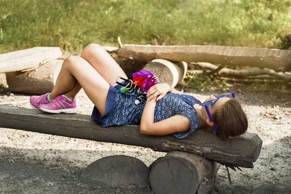 Jonge vrouw zittend op houten bank in openbaar park met weide en natuur achtergrond — Stockfoto