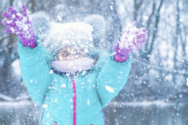 Kışın kar altında, mavi ceketli bir kız. Sokakta eğlenmek. Kış soğuğu. Soğuk bir günde yürüyüşün tadını çıkarır.
