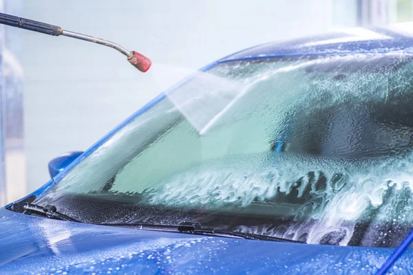 Ручна мийка автомобіля з водою під тиском в автомийці зовні. Очищення автомобіля Використовуючи воду високого тиску . — стокове фото