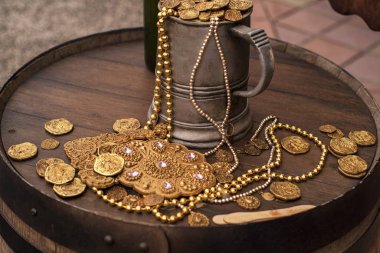 Yapay altın sikkeler ve tahta bir fıçının üzerindeki süsleme. Altın ve yapay paralarla dolu bir kupa. Jack Sparrow paralar..