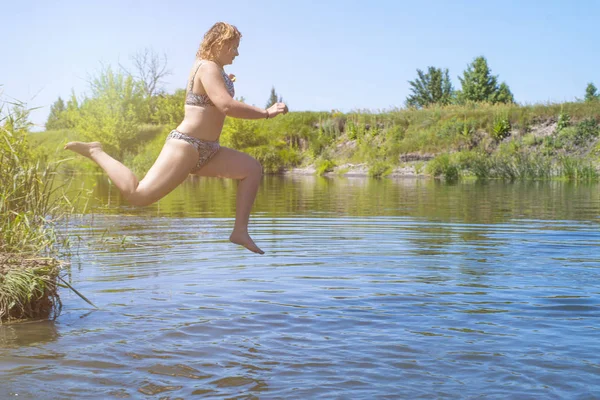 Nő ugrik, mint a hal a vízbe a tó, úszik, élvezi tölteni az időt a nyári szünetben. Nő ugrik a folyóba. — Stock Fotó