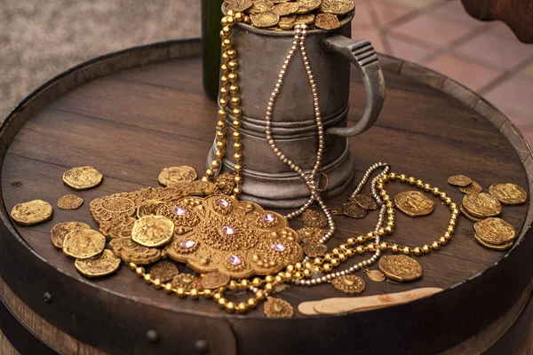 Monedas de oro artificiales y una decoración en un barril de madera. Una taza llena de monedas artificiales de oro.Jack Sparrow coins . — Foto de Stock