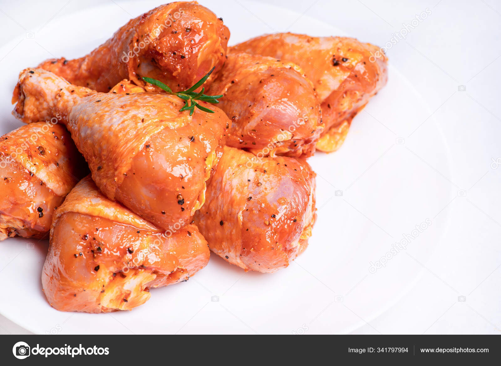 Chicken legs in a red marinade on a white plate. Top view. Chicken meat