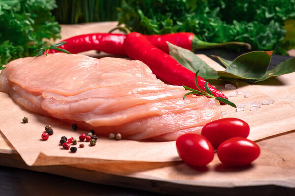 Raw chicken slices on a wooden table with raw vegetables and spices. Sottilissime. Delicious dietary meat. Close-up view of raw, fresh, choped and sliced chicken meat. Cooking,raw sliced chicken breast.