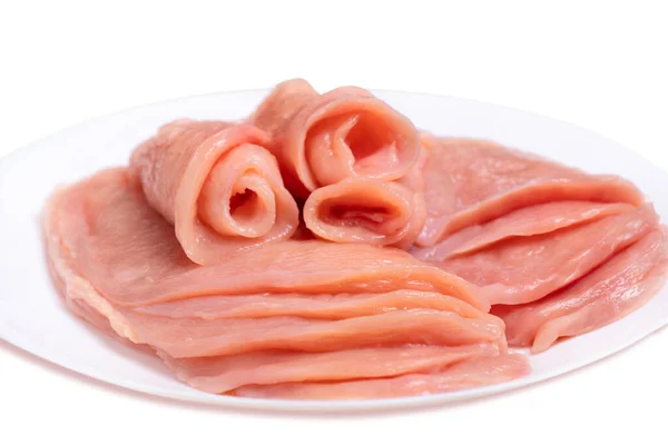 Raw sliced chicken meat close-up on a white plate and on a white background. Sottilissime. Delicious dietary meat. Culinary. Top view. — Stock Photo, Image