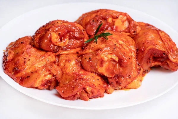 Chicken legs in a red marinade on a white plate. Top view. Chicken meat close-up.Dietary meat. Cooking.Raw marinated chicken legs for grill and bbq.Isolate. — 图库照片