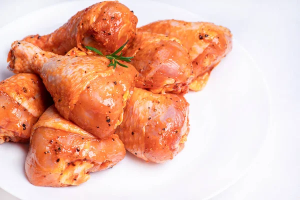 Chicken legs in a red marinade on a white plate. Top view. Chicken meat close-up.Dietary meat. Cooking.Raw marinated chicken legs for grill and bbq.Isolate. — 图库照片