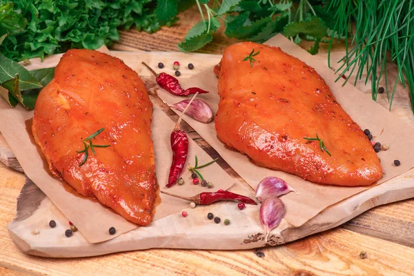 Marinated Chicken Breast with spices rosemary and vegetables on a cutting board and on a wooden table. Top view. Tasting diet meat.Chicken meat closeup. Raw meat in marinade.
