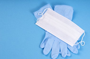 Cerrahi koruyucu maske. Mavi arka planda mavi eldivenli tıbbi beyaz maske. Coronavirus COVID karantinası. Wuhan salgını. Tehlikeli Çin Roman virüsü COVID-19.