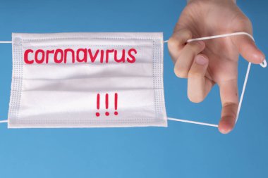 Çin 'de koronavirüs salgını. Mavi arka planda Coronavirüs yazılı koruyucu bir maske var. Coronovirus Karantina Konsepti..