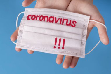 Çin 'de koronavirüs salgını. Mavi arka planda Coronavirüs yazılı koruyucu bir maske var. Coronovirus Karantina Konsepti..