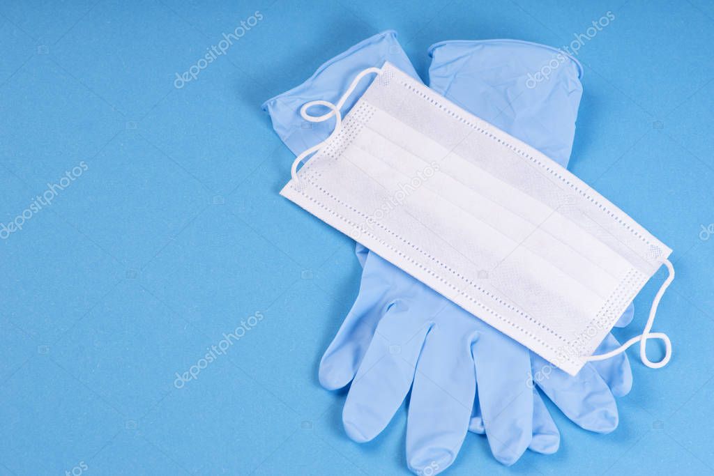 Surgical protective mask. Medical white mask with blue gloves on a blue background. Concept coronavirus COVID quarantine. Wuhan epidemic outbreak. Dangerous Chinese Novel virus COVID-19.