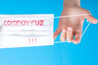 Dünya çapında koronavirüs salgını. Coronavirüs 'ün mavi arka planında bulunan beyaz koruyucu bir maske. Biyoteknoloji kavramı. Coronavirüs pnömonisi COVID-19.