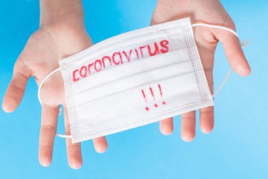 Dünya çapında koronavirüs salgını. Coronavirüs 'ün mavi arka planında bulunan beyaz koruyucu bir maske. Biyoteknoloji kavramı. Coronavirüs pnömonisi COVID-19.